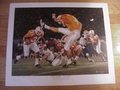 Picture: This print has a scratch mark in the right upper half not on the image area. Because of this it is half price. Normally this print sells for $149.99 but we are taking $75 off because of the scratch. We only have one print like this and one other on the website in excellent condition. Tennessee Volunteers "Victory- At Last" is a signed printer's proof by artist Alan Zuniga. The print celebrates UT's win over Florida in 1998 which led to the Vols winning the National Championship. This print shows Jeff Hall's game-winning field goal in overtime, Jamal Lewis running through the Florida defense, and Darwin Walker nailing quarterback Doug Johnson.